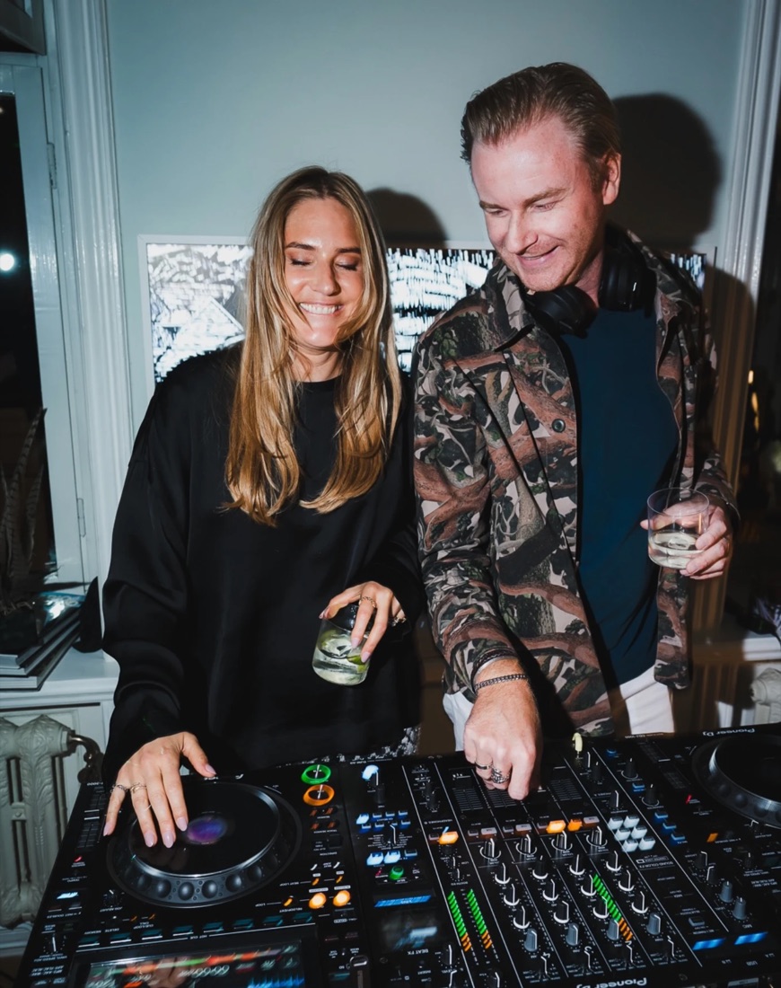 The birthday girl and the DJ laughing together behind the decks